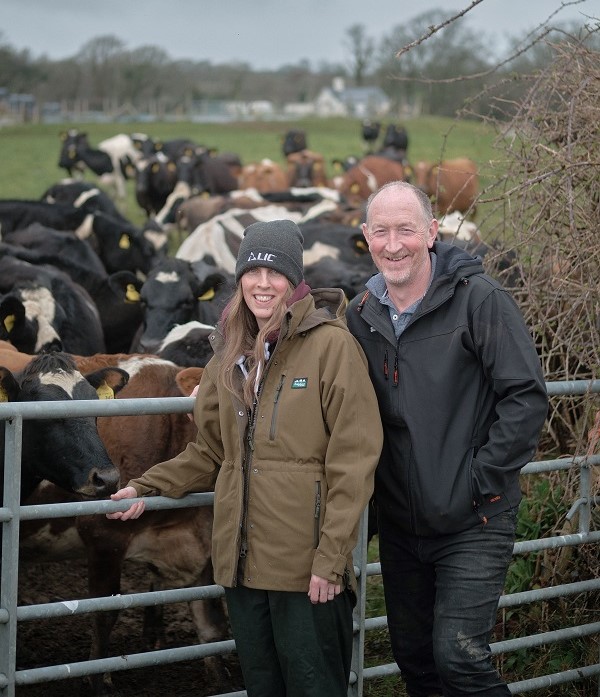 Tegid and Hannah Williams standing in front of a herd of cows.
